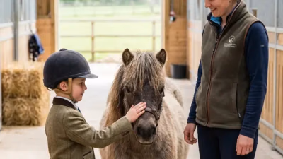 Kind steht ruhig neben einem kleinen Pony und hält den Führstrick locker in der Hand