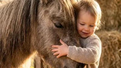 Kind beim therapeutischen Reiten mit Ball.